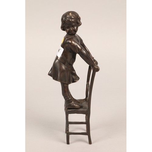 238 - Bronzed girl figure standing on a chair.