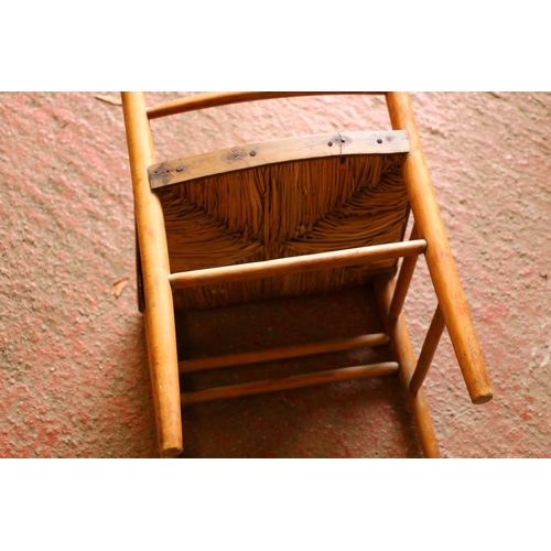 707 - Child's beech chair, with spindle back and rush seat, raised on turned supports, united by stretcher... 