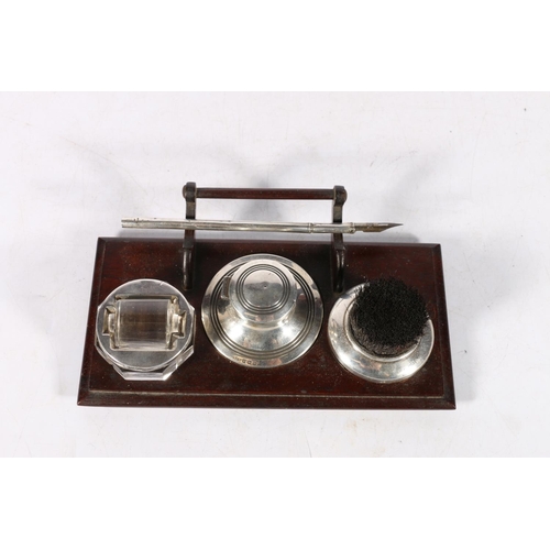 85A - Silver and wood desk tray fitted with a capstan inkwell, a nib wipe and a stamp or envelope roller, ... 