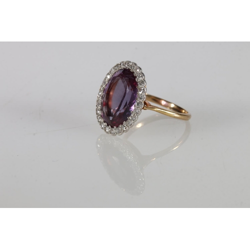 179 - Unhallmarked yellow metal dress ring, the large central faceted oval amethyst encircled by 26 small ... 