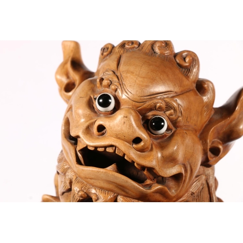 555 - Chinese carved wood fu dog model with glass eyes modelled standing with infant, 39cm tall.