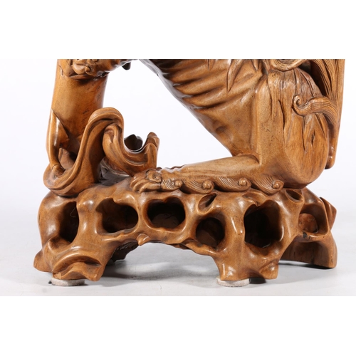 555 - Chinese carved wood fu dog model with glass eyes modelled standing with infant, 39cm tall.