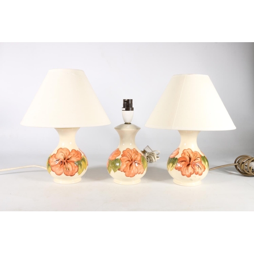 472 - Trio of Moorcroft hibiscus pattern table lamps, 2 with shades, 30cm to top of shades.