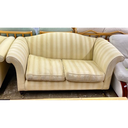 526 - Pair of lemon upholstered two seater sofas on turned legs with brass castors (2)