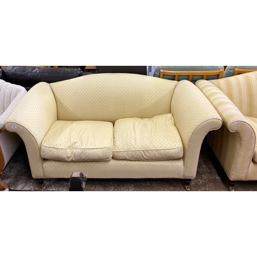 526 - Pair of lemon upholstered two seater sofas on turned legs with brass castors (2)