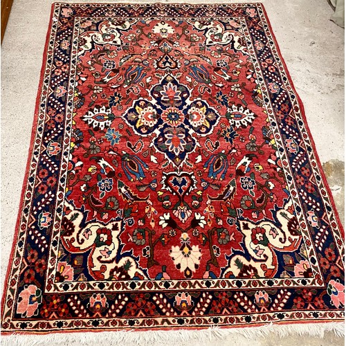 605 - Middle eastern style woollen rug, on red ground , 209 x 148 cm