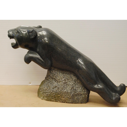 358 - Polished granite figure of a jaguar raised on a naturalistic rock base, approximately 37cm high and ... 