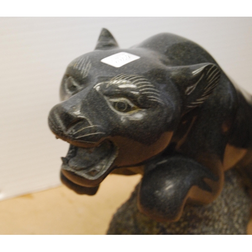 358 - Polished granite figure of a jaguar raised on a naturalistic rock base, approximately 37cm high and ... 