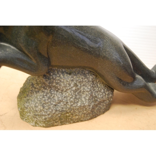 358 - Polished granite figure of a jaguar raised on a naturalistic rock base, approximately 37cm high and ... 