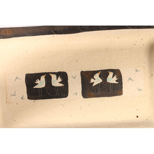 65 - Studio pottery shallow dish of rectangular shape decorated with spirals and birds, signed Michal to ... 