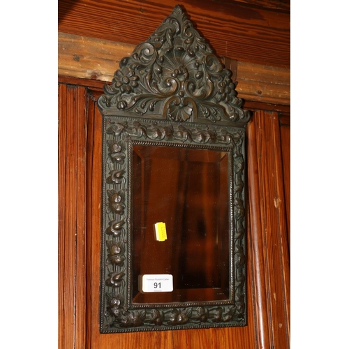 91 - Early 20th century bevel edged cushion type mirror with high relief floral decorated frame,  44cm.