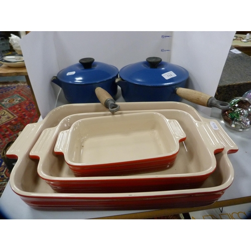 114 - Two Le Creuset pans with covers, glazed in blue, and a set of three Le Creuset graduated oven dishes... 