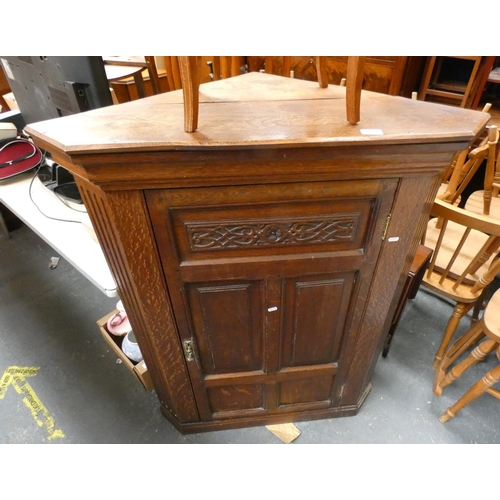 558 - Carved oak corner cupboard enclosed by a single door.