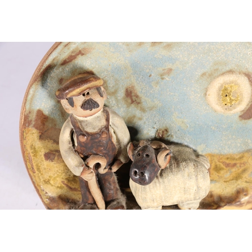 43 - Moffat Pottery circular wall plaque, shepherd with sheep, signed to reverse 'Flockfield' and dated 1... 