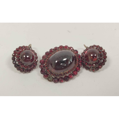 120 - Pyrope garnet oval brooch, with tiered cabochons and the matching drop earrings, 'garnet gold'.  (3)