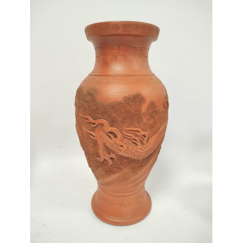 340 - Four Oriental terracotta vases of baluster form and bottle shape, all bearing relief dragon decorati... 