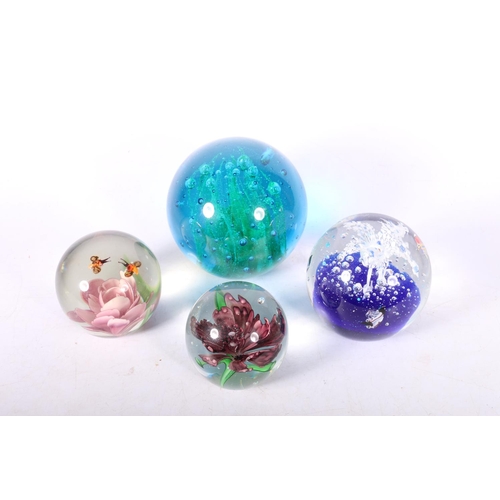 77 - Four glass paperweights.