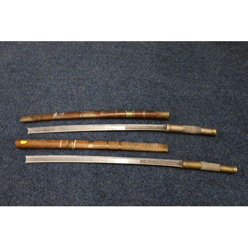 744 - Two Burmese dha swords, the curving blades with incised scrolling design, fish skin and brass handle... 