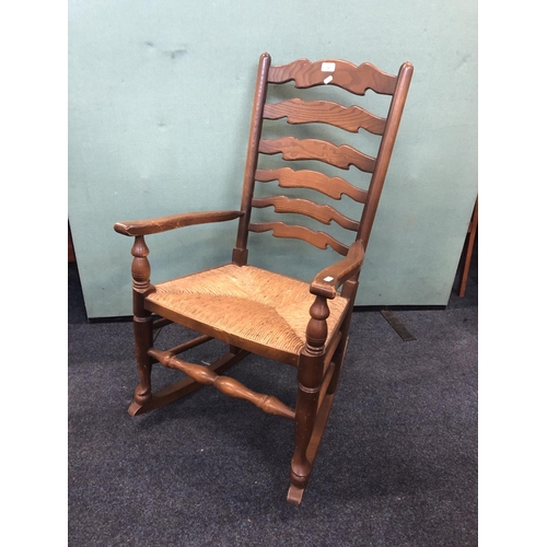 740 - Elm ladder back rocking chair with rush seat, 98cm.