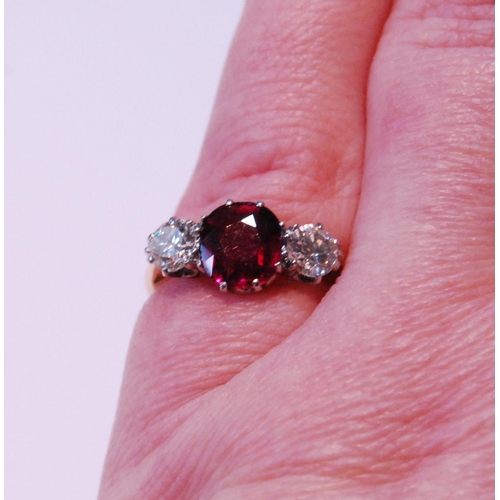 3 - Three-stone ruby and diamond ring, the almost-circular ruby approximately 6mm x 7mm, with two old-cu... 