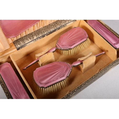 56 - George V silver and pink guilloche vanity set to include hand mirror, 30cm, and four brushes, hallma... 