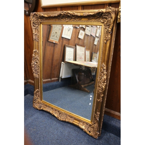 566 - Antique style gilt bevelled edge wall mirror with ornate scroll border, 154cm x 121cm.