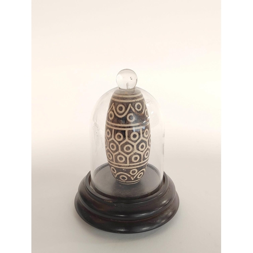 344 - Tibetan inlaid Dzi Bead with all over geometric decoration, 9cm long, enclosed in a glass dome case.