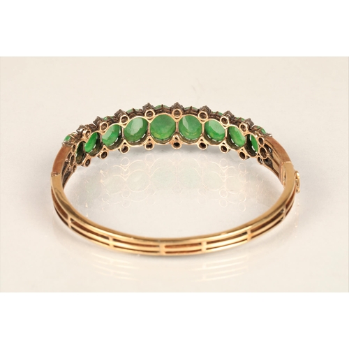 109 - Ladies yellow metal stiff bangle set with nine oval cabochon jade stones, surrounded by twenty two s... 