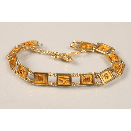 82 - Ladies unmarked yellow metal bracelet with symbols with an attached gold nugget pendant, length 19cm... 