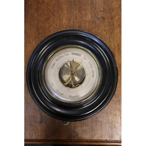 294 - Circular bulkhead barometer in ebonised frame, 27cm diameter.