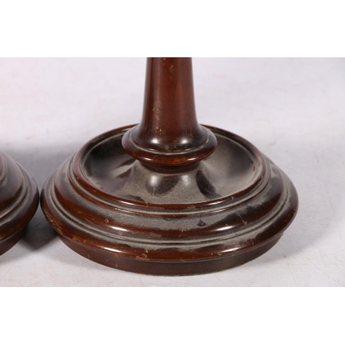 277 - Pair of turned mahogany loaded candlesticks, with brass drip trays, 21cm high.  #196