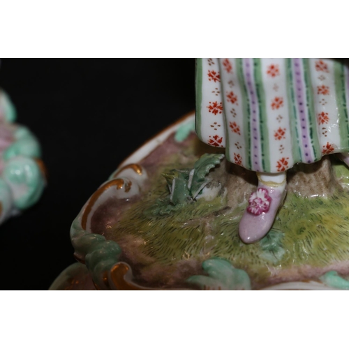 303 - Pair of 19th Century Meissen candlesticks in the form of a man and woman supporting baskets to their... 