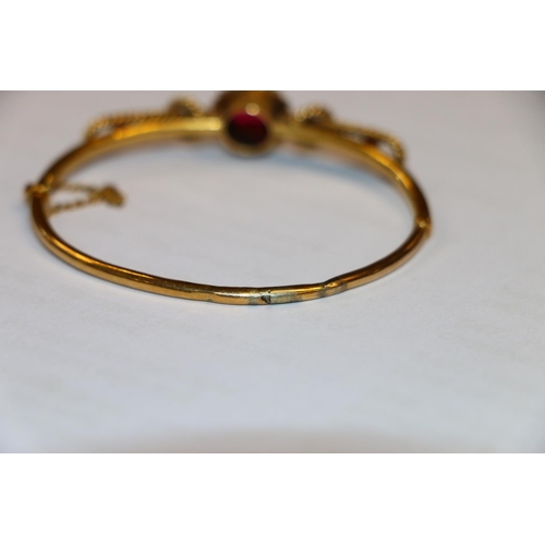 131 - Victorian yellow metal bangle set with seed pearls and faceted red stones, 10g gross. #368