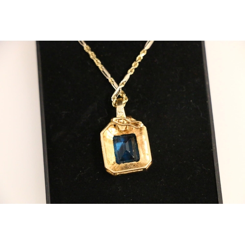 133 - 14ct gold pendant set with a vibrant blue rectangle cut stone, on 14ct gold chain 23cm, 11.4g.