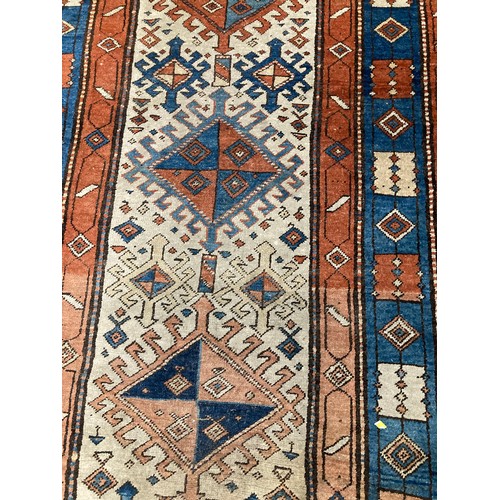 813 - Caucasian runner with hooked medallions within geometric borders, 470 x 110cm.