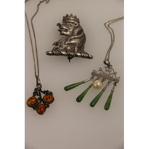 504 - Silver and amber pendant on chain, a silver and green hardstone pendant on chain, and a white metal ... 