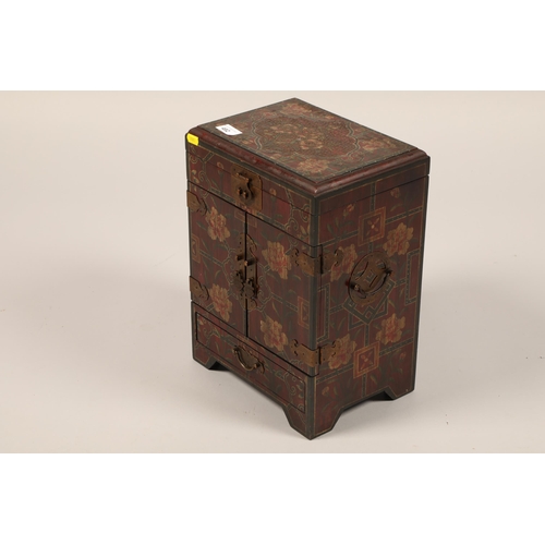 492 - An oriental lacquered table cabinet, hinged cover over pair of decorated doors, enclosing three draw... 