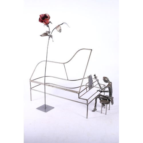 284 - Metal sculpture of a figure at a piano, along with a metal flower, 47cm high.