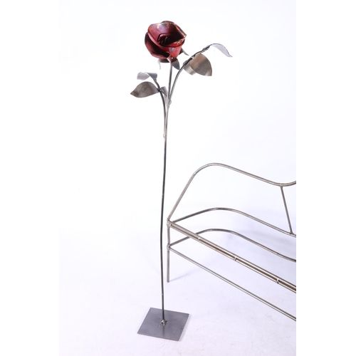 284 - Metal sculpture of a figure at a piano, along with a metal flower, 47cm high.