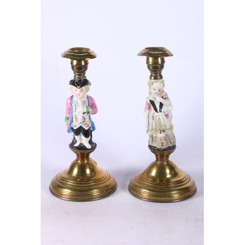 106 - Pair of candlesticks with ceramic figures to centre, brass tops and bases, 20cm high.