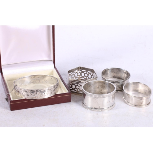 597 - Silver hinged bangle, hallmarked D A, Birmingham 1976, and four napkin rings, 106g.