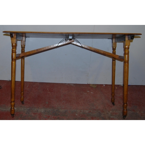 356 - Ash and oak trestle-style folding table, the rectangular top on turned supports and castors united b... 