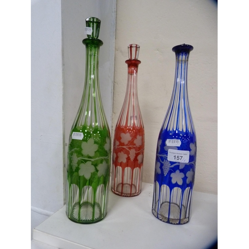 157 - Three Edwardian-style coloured flash-cut decanters, in ruby, blue and green, and two decanter stoppe... 