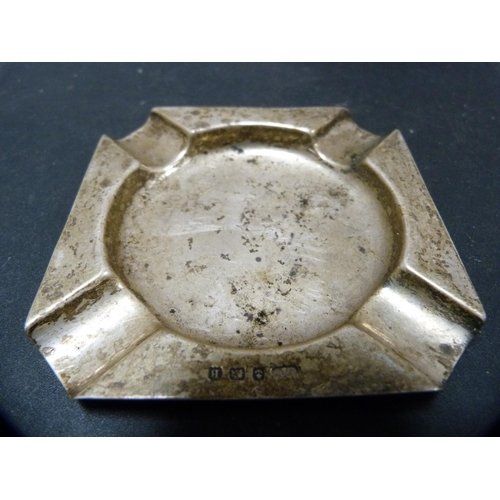 274 - Silver stand and a silver ashtray, 130g gross, also an unmarked white metal vesta sleeve, pin dish a... 