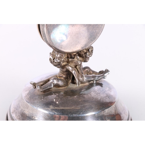 706 - Silver watch stand with cherub supporters. 