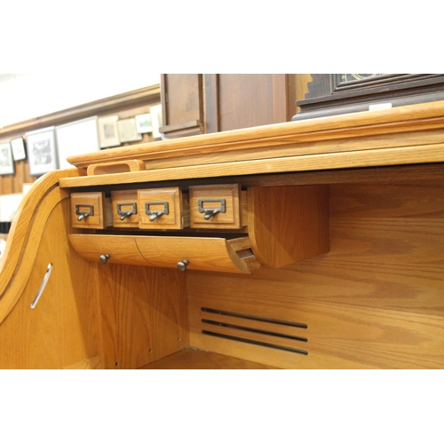 745 - Oak twin pedestal roll top desk with fitted interior, 138cm wide.