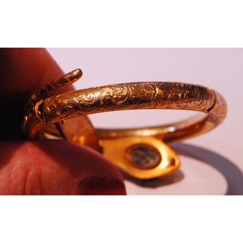 32 - Fine Victorian gold snake bangle, hinged in six sections, engraved with scrolls, the head with caboc... 