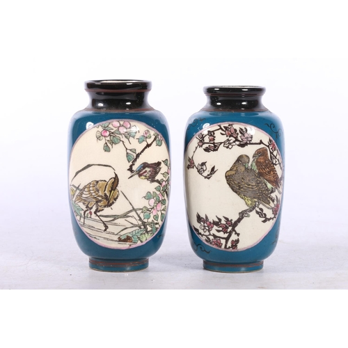 117 - Pair of blue ground vases decorated with panels of birds, 11cm.