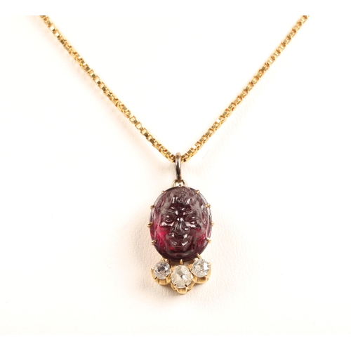 72 - Deep purple stone carved in the form of a face set in yellow metal above three diamonds, on 18ct gol... 