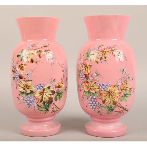 271 - Pair of semi-opaque pink overpainted glass vases, decorated with flowers, 27cm high.